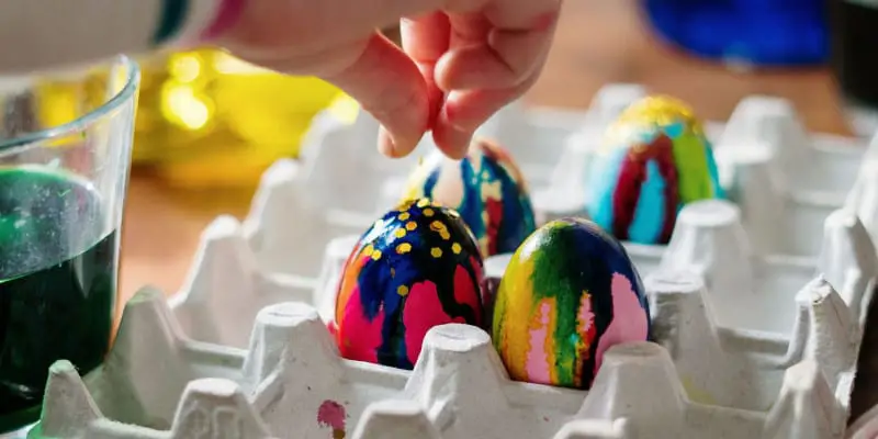 child decorating colorful eggs