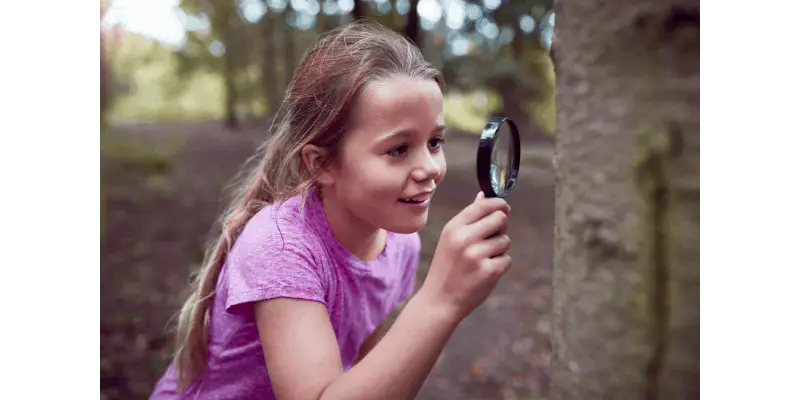 Young girl using a magnifier to study a tree