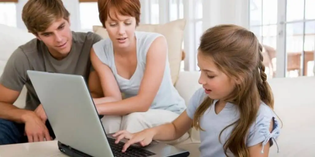 Parents watching child typing on keyboard laptop
