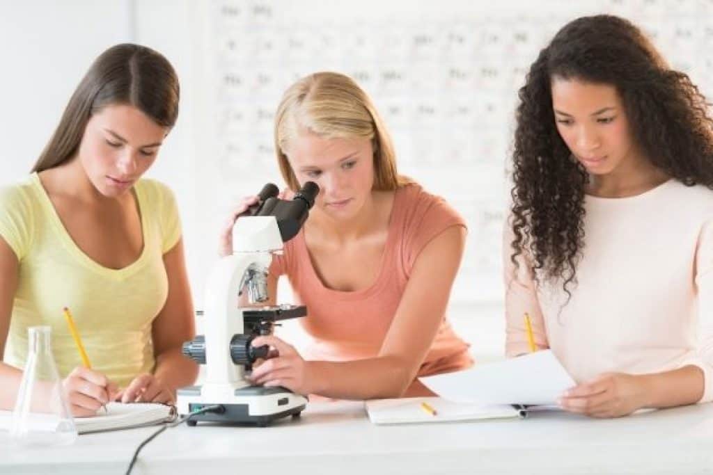 Girls doing science research with microscope