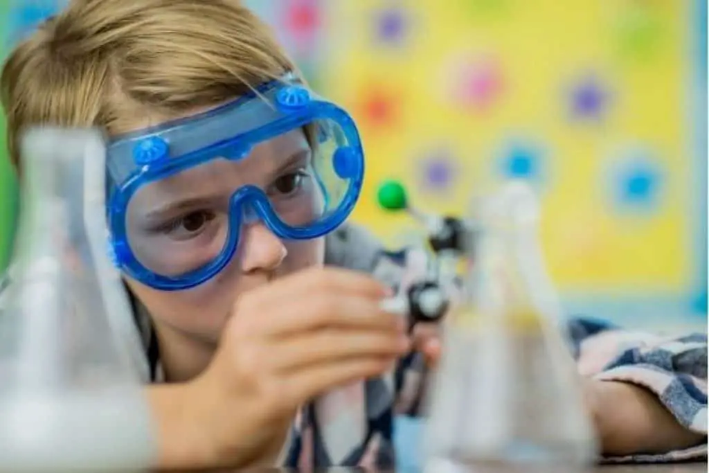 Teenager with lab safety goggles holding a molecular model