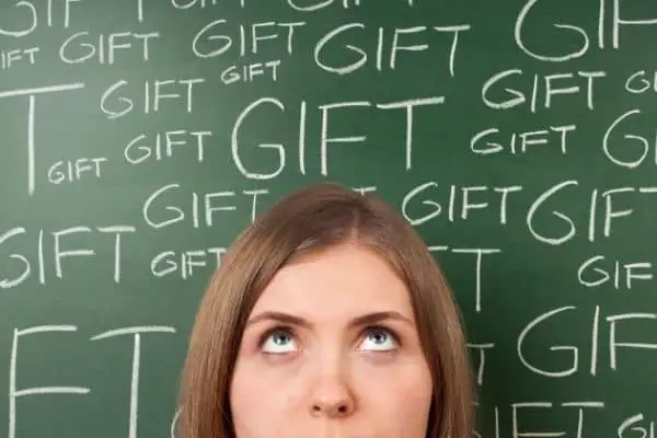Woman thinking surrounded by gift text in the blackboard at the back