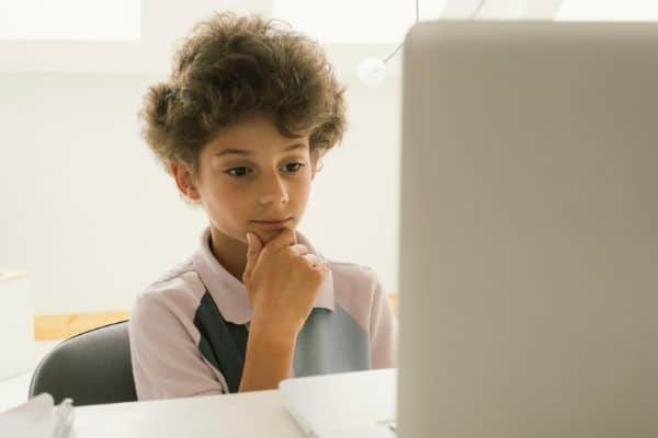 Kid thinking while looking at computer screen