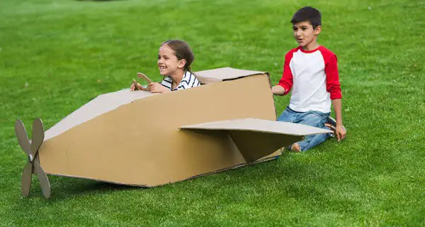 Kids playing with homemade cardboard airplane