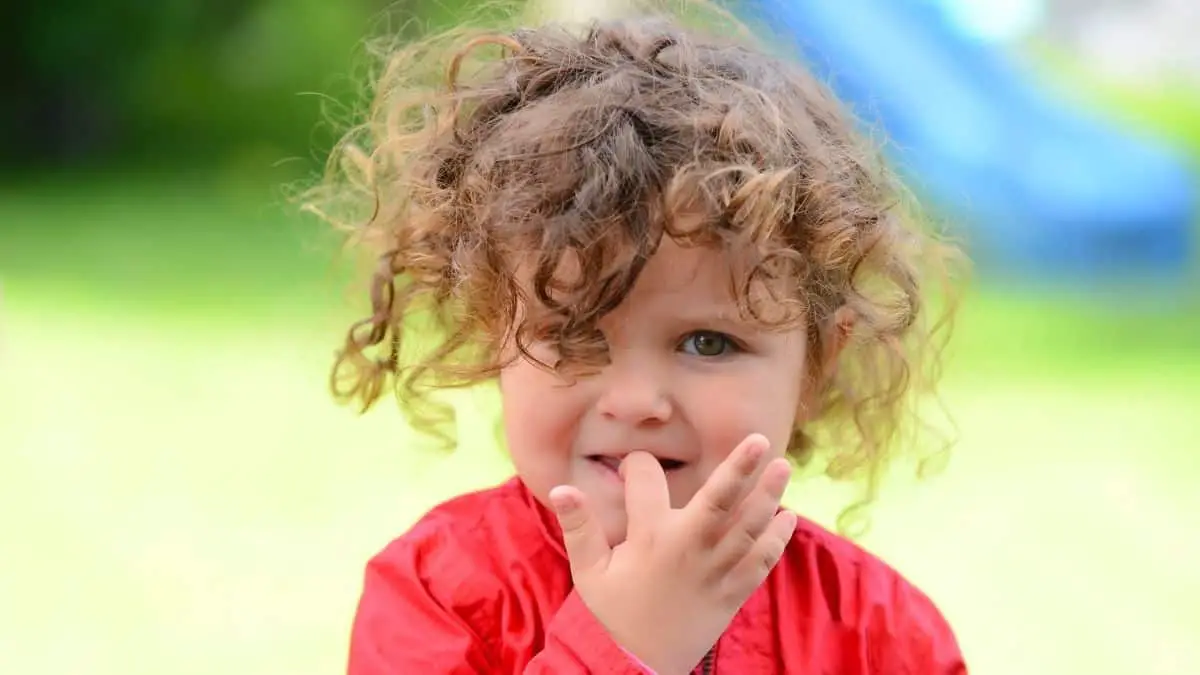 Little girl with curly hair biting her nails - maybe a fidget toy will help