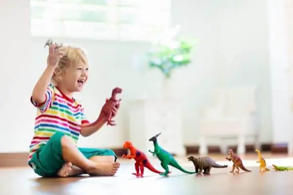 child happily playing with different dino toys