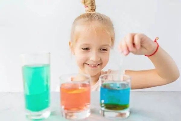 Smiling Child Doing Liquid Experiment With Juice And Food Color
