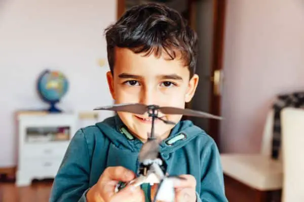 A Boy Holding A Small Helicopter