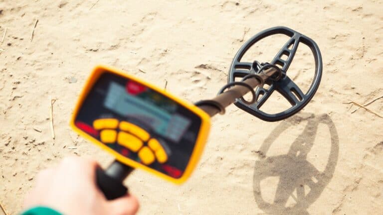A Person Holding A Yellow Metal Detector At The Beach